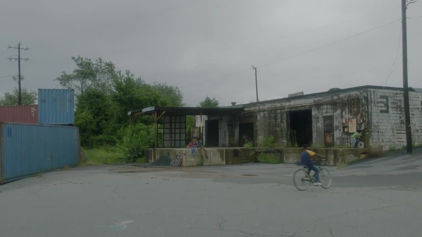 A child rides his bike around the lot of an abandoned building