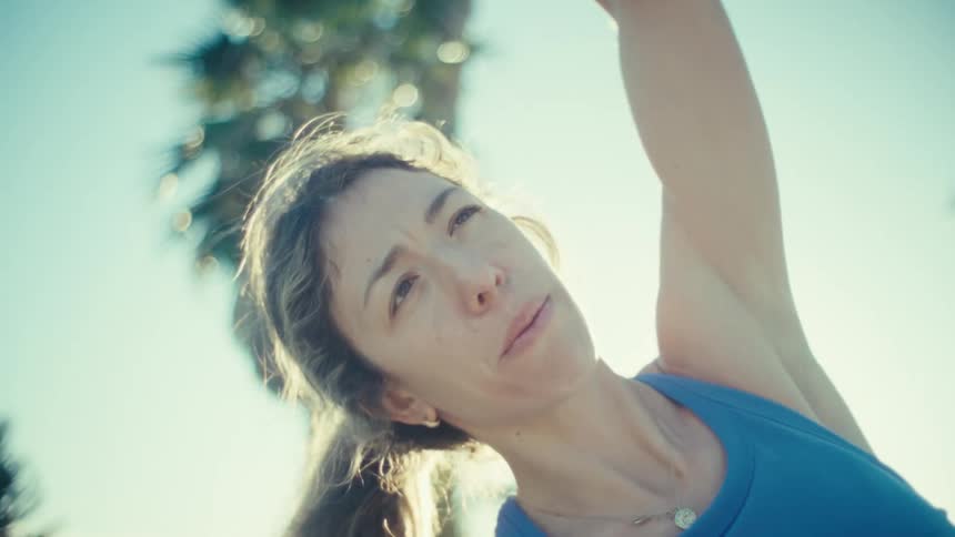 Sunlight shines on a pregnant woman doing stretching exercises on the beach