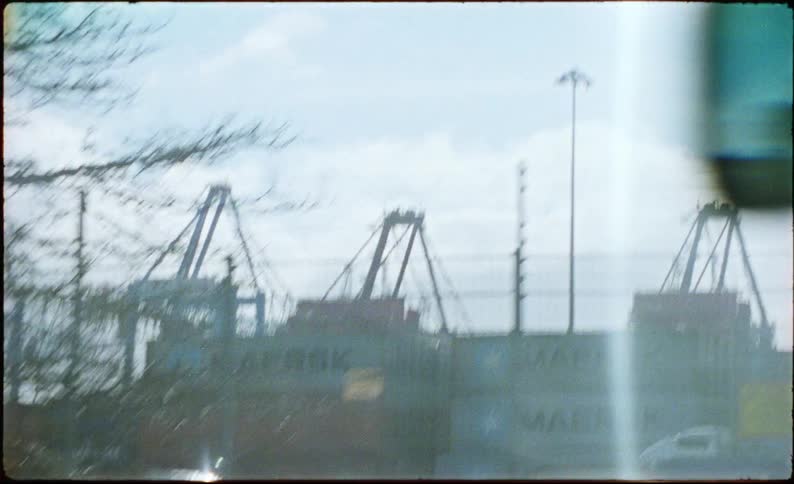 Traffic is moving next to several buildings and cranes