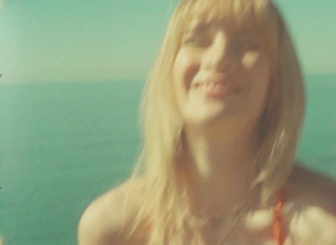 A woman standing on cliffs near a beach while wearing a bikini