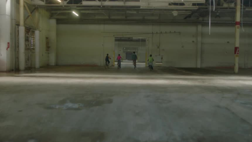 People riding bicycles through an open area in a building