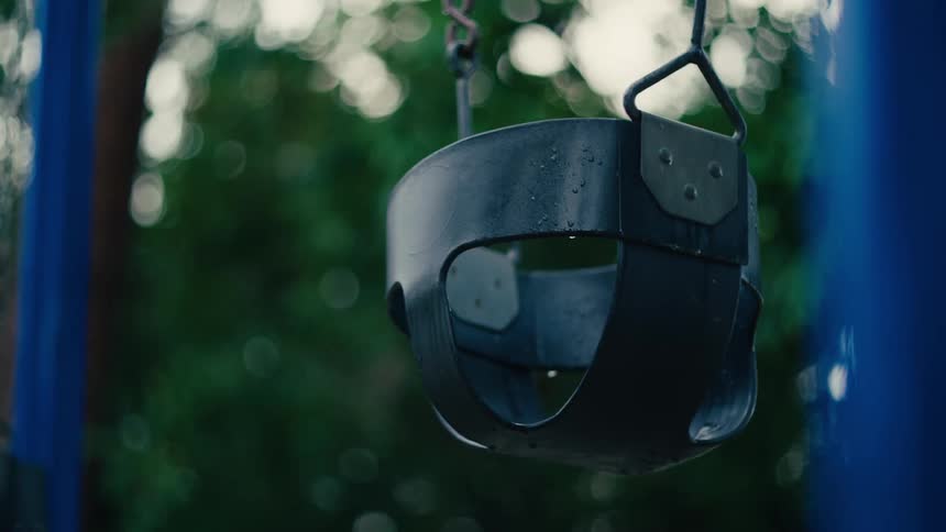 A childs swing on a playground sways in the wind