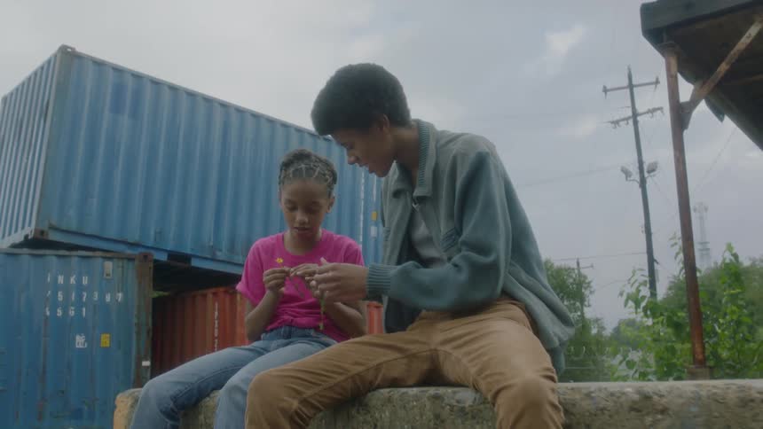A young boy and girl sit looking at flowers