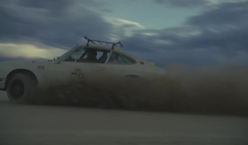 White rally car driving on a desert area with mountains on the background outdoors during dusk or dawn