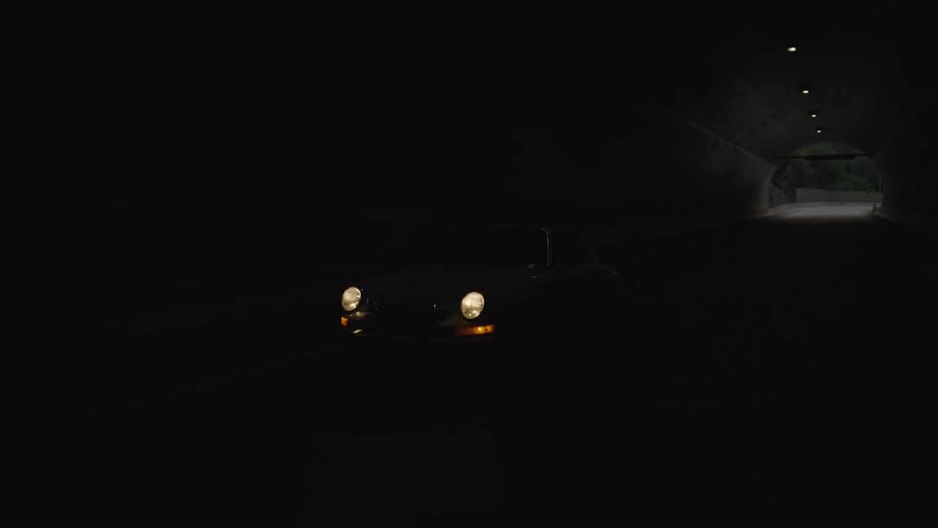 A vintage porsche with its headlights blazing drives through a dim tunnel toward an arched opening that reveals a winding mountain road at dusk