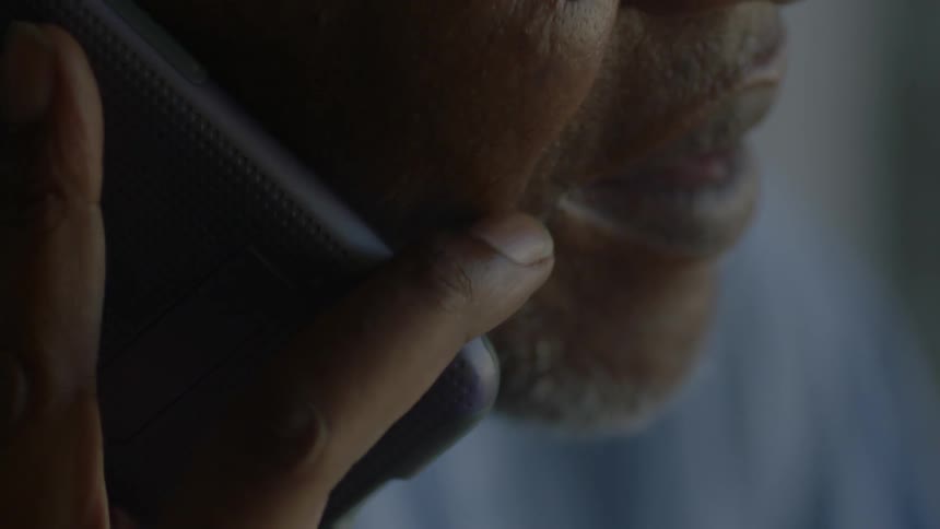 Close-up of a man talking on a cell phone indoors