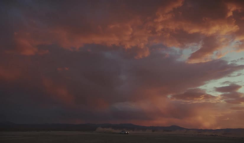 Dense orange clouds over a mountain horizon and body of water at sunset