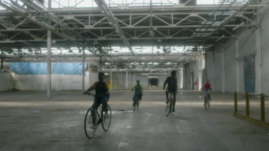 Kids ride their bikes in an empty warehouse