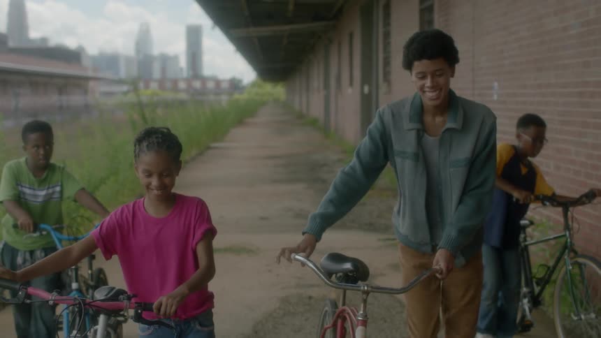 Four children push bikes outside of a building
