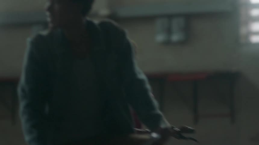 Two child ride bikes in an empty warehouse