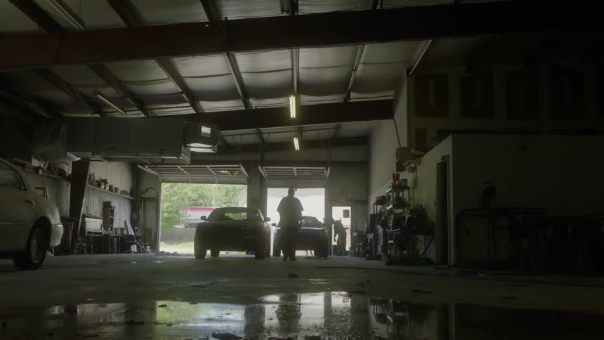 A man walks towards cars parked in a large garage