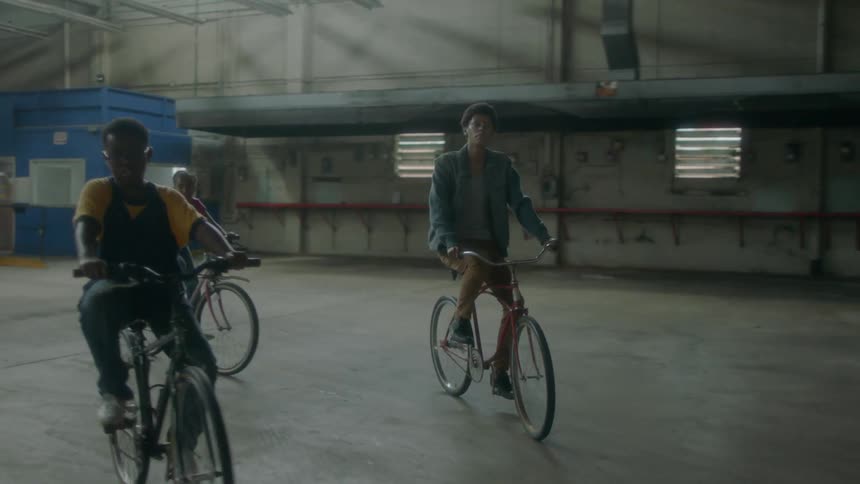 A group of kids ride bikes inside a building