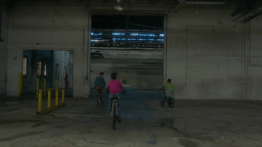 Kids riding bicycles through an empty warehouse