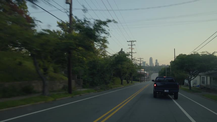 Truck traveling down neighborhood street towards large city