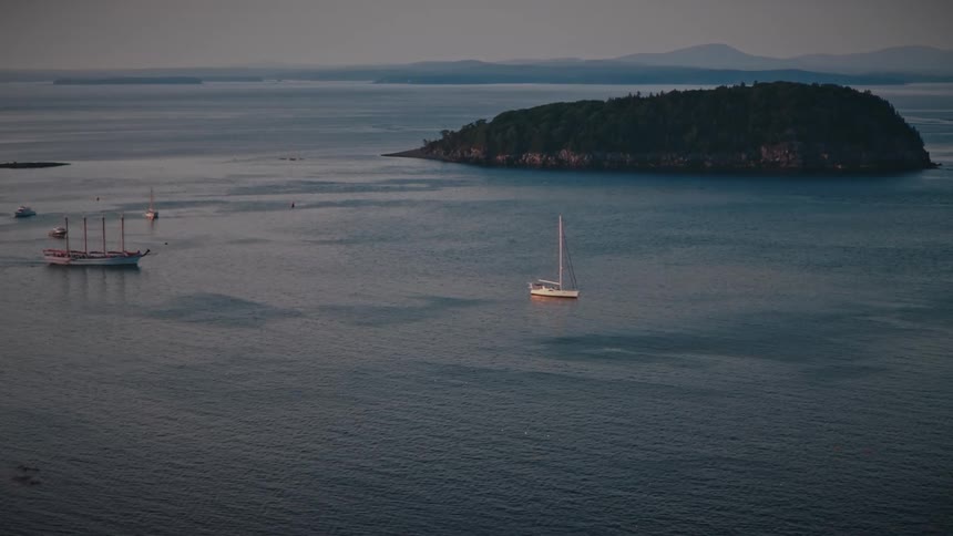 Boats sailing on the water near an island off the coast