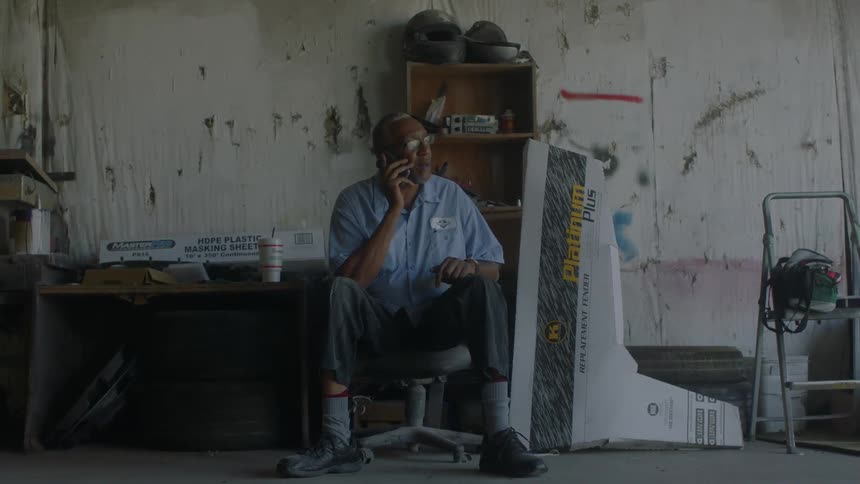 Man sits in a workshop talking on a phone