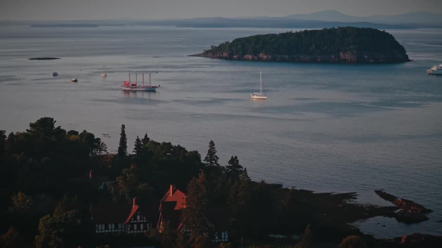 Boats sailing on the water near an island off the coast