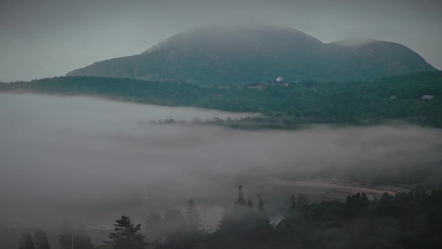 A sea of fog fills the valley as a distant mountain ridge rises above the mist