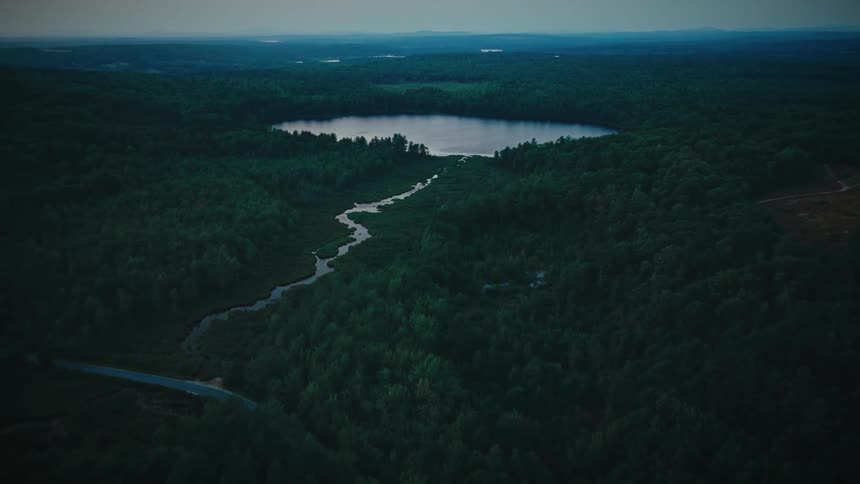 An aerial view of a river coming from a lake near some trees