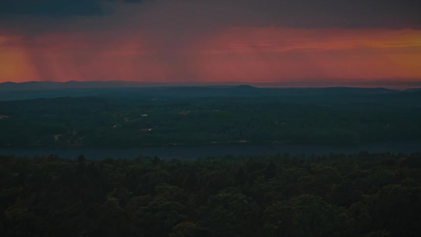 Rain is falling in the distance as the sun sets