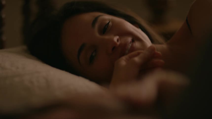 A woman smiles talking to someone in bed