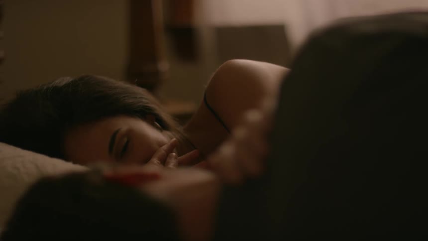A man and woman are lying in bed looking at each other