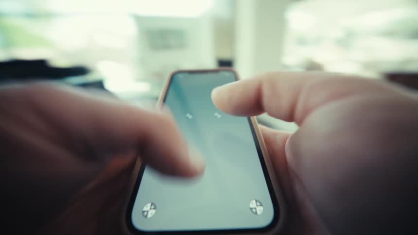 A close view of hands holding a smartphone and typing on the screen with both thumbs in a bright indoor setting