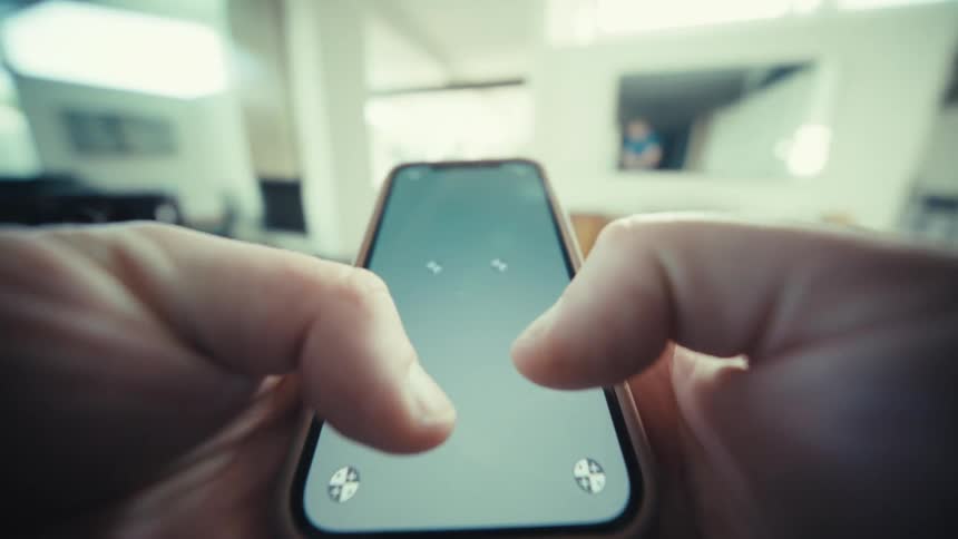 A close view of hands holding a smartphone and typing on the screen with both thumbs in a bright indoor setting