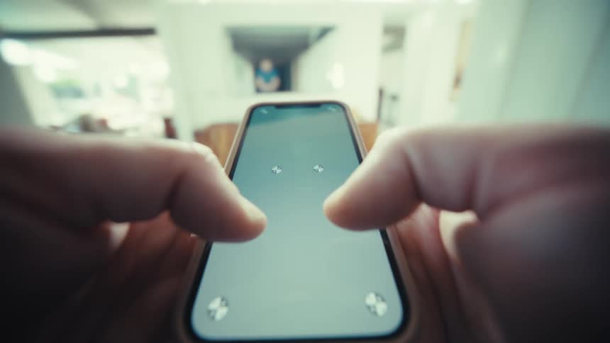 Man holds his smart phone with both hands as he presses his thumbs on the screen