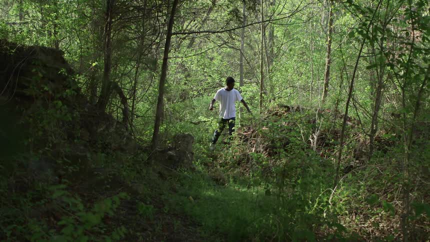 A boy walks through a wooded area