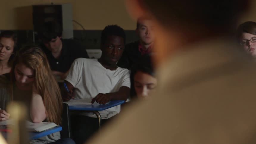 Classmates sitting at their desks as the teacher lectures