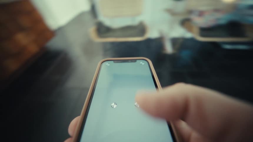 Hand holds smartphone displaying a loading indicator on the screen indoors