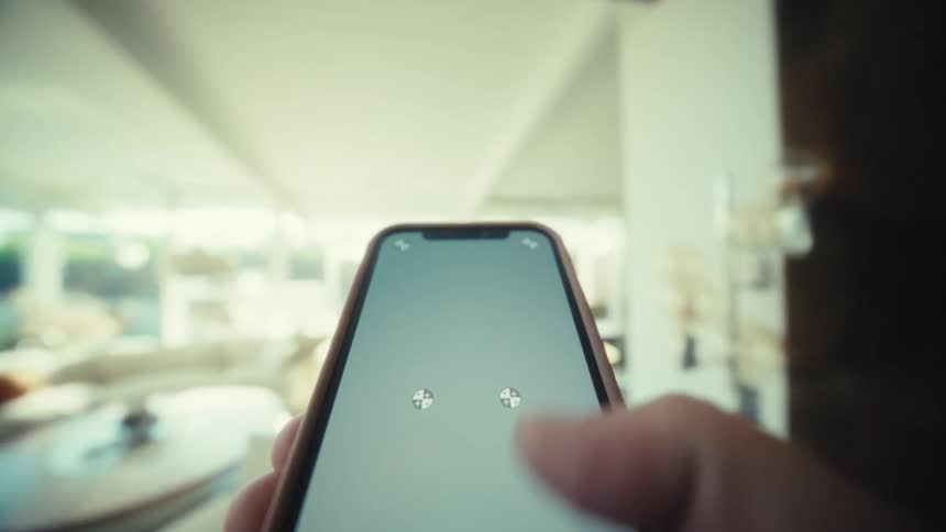A person holds a smartphone while walking through a bright modern house with an open floor plan