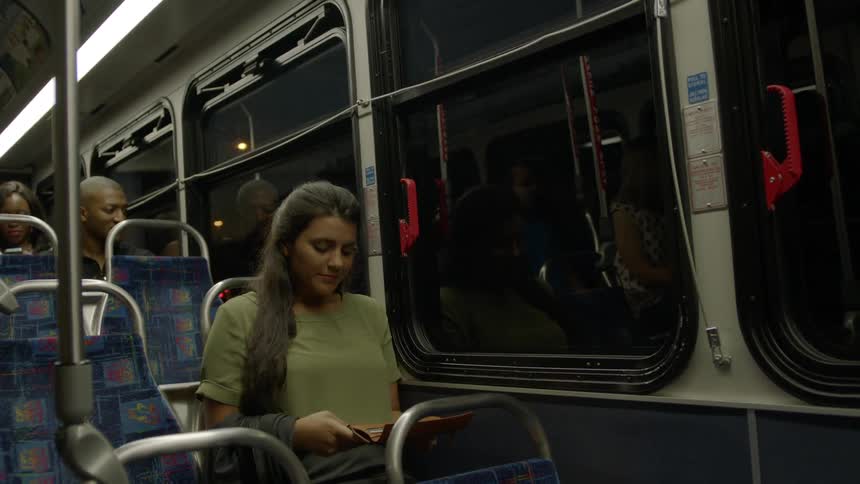 A woman rides a bus at night