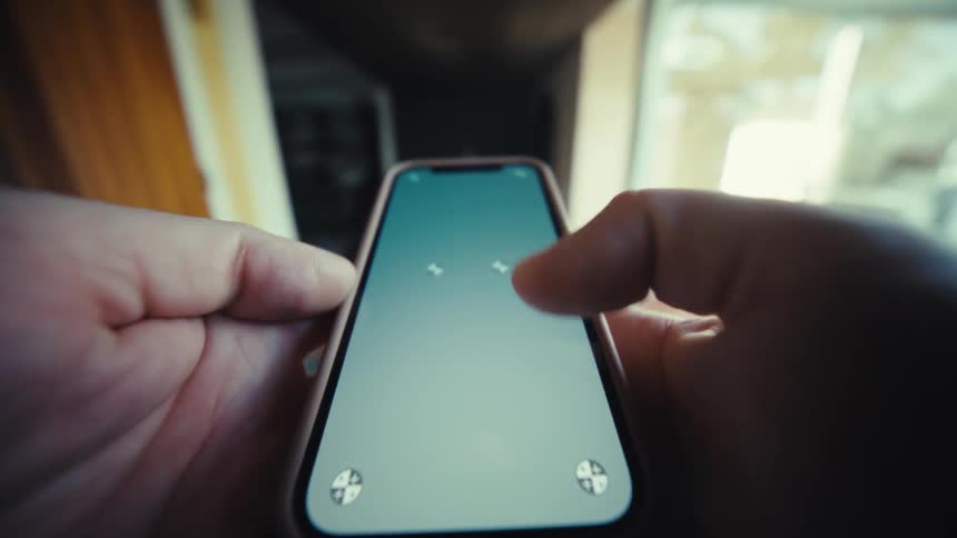 Fingers type on a smartphone held with both hands in an indoor corridor