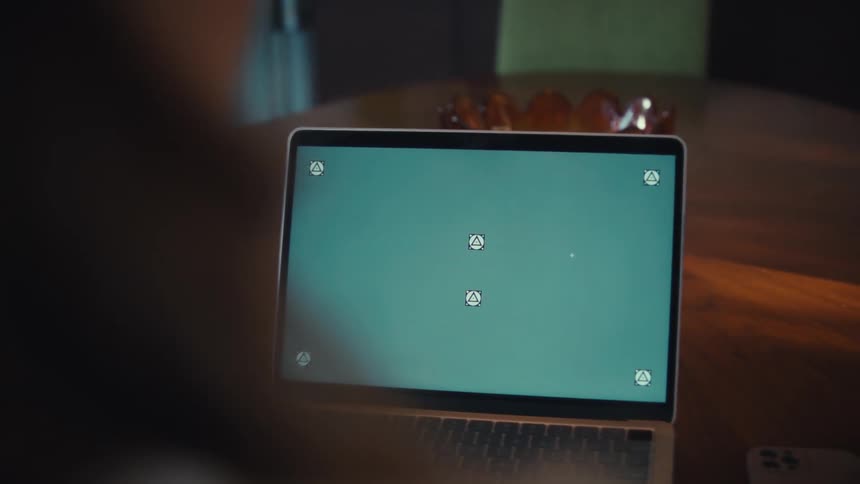 Open laptop on a table displaying a blank screen with a smartphone beside it