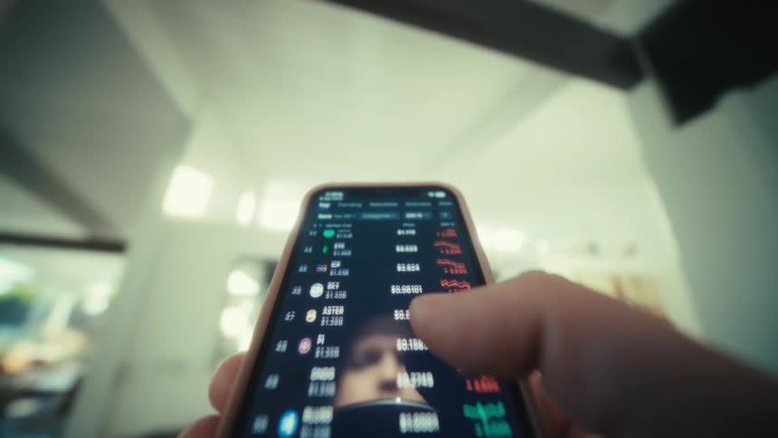 Man holds a smart phone in his hand moving his thumb across the screen to scroll as his reflection is seen on the screen