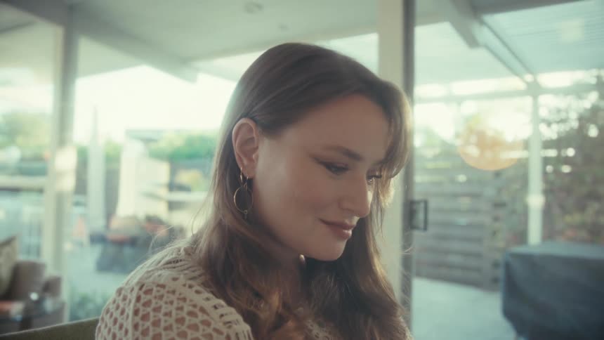 Woman wearing circular earrings looks downward in a lit indoor setting