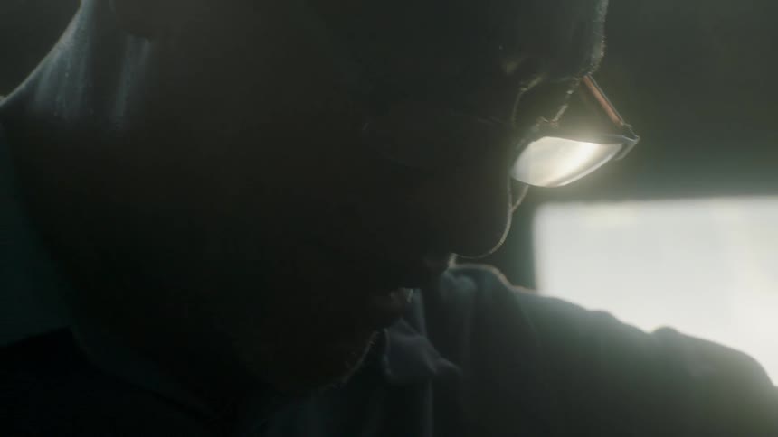A man wearing glasses looks downward