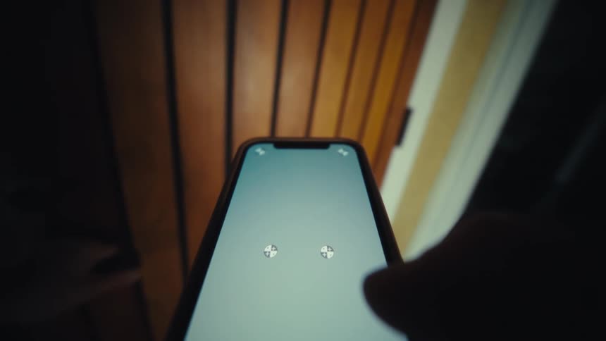 A person holding a smart phone walks through a large residence