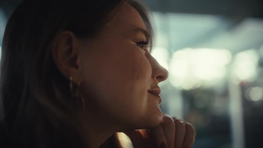 A woman types on a laptop then stops to think with her hand under her chin