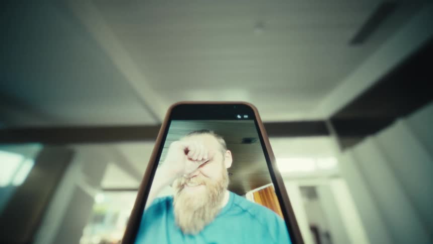 Smartphone displaying front camera with bearded man on the screen