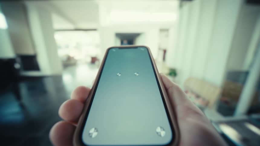A person holds their cellphone out as they walk through an office
