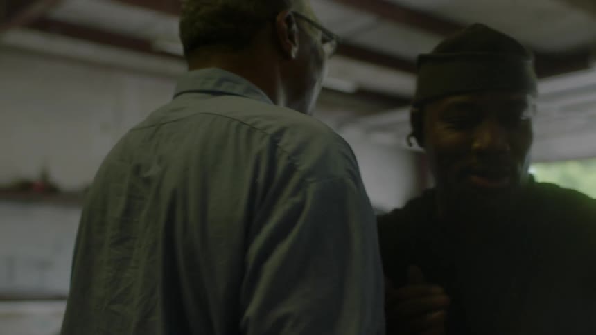 Two smiling men shake hands and hug in a garage