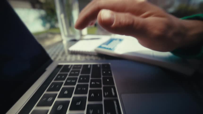 Hand typing on a laptop keyboard in side closeup