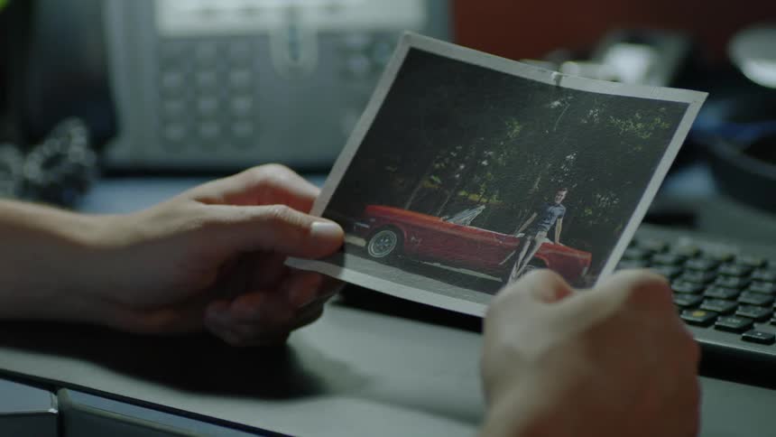 A person is holding an old photo as they sit at a desk