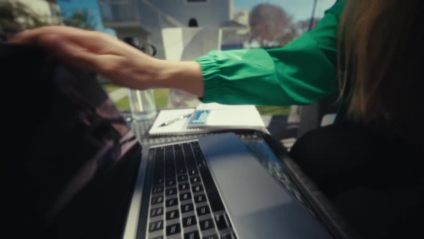 Hand turning off a laptop on an outdoor table