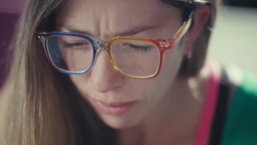 Woman wearing multicolored glasses looking downward