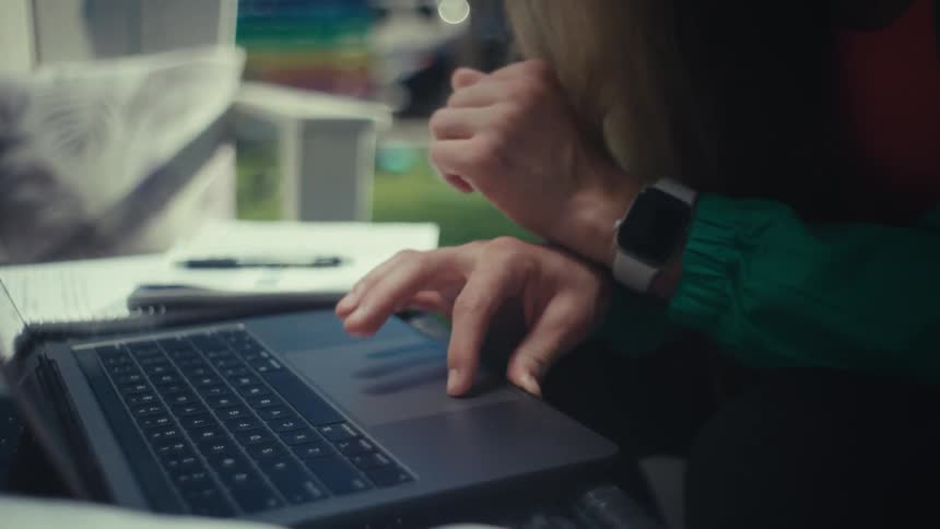 Woman types on a laptop while wearing a smartwatch on her wrist
