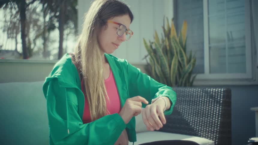 Pregnant woman tapping a smartwatch while seated outdoors